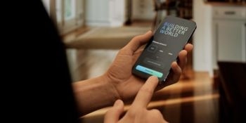 A person holds a smartphone displaying a login screen with the text 