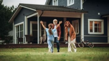 Grandparents happily greet their granddaughter outside a family home, symbolizing efforts to protect inheritance across generations, including from risks like divorce.