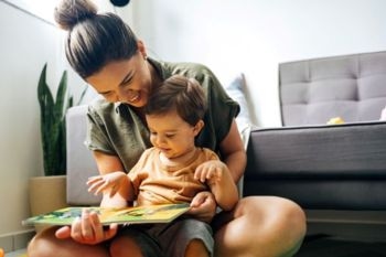 A parent reviewing legal documents with a lawyer while their child plays nearby