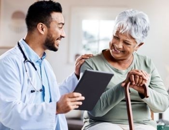 Smiling doctor discussing medical documents with an elderly woman using a cane