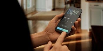A person holds a smartphone displaying a login screen with the text 