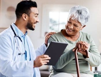 Smiling doctor discussing medical documents with an elderly woman using a cane